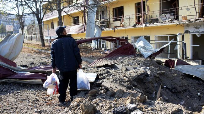 Мужчина возле дома, пострадавшего в результате обстрела города Шуша
