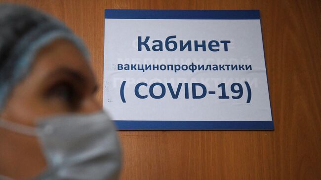 Медицинский работник у кабинета вакцинопрофилактики