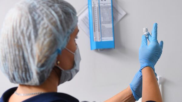 Медицинский работник набирает в шприц вакцину против COVID-19 