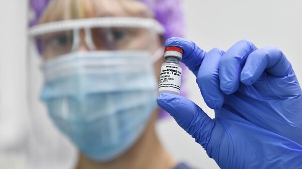 Медсестра городской поликлиники №7 в Симферополе держит в руках ампулу с вакциной Гам-Ковид-Вак