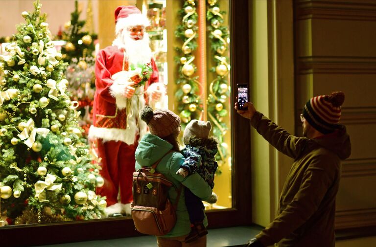 Прохожие фотографируют Санта Клауса в витрине на Никольской улице в Москве