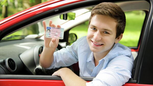 Молодой человек демонстрирует водительское удостоверение