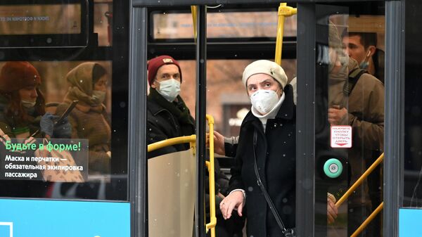 Люди в защитных масках на остановке общественного транспорта на Ленинском проспекте в Москве