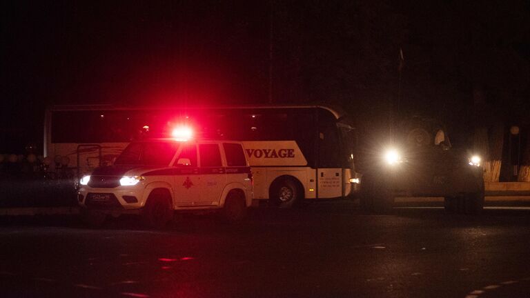 Бронемашина миротворцев и полицейская машина сопровождают автобусы с беженцами из Нагорного Карабаха, вернувшимися в Степанакерт из Еревана