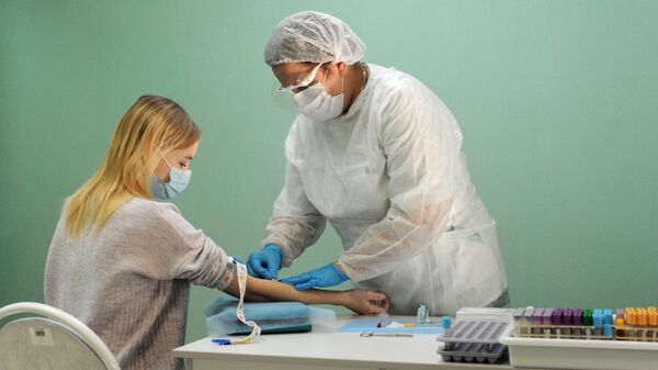 Медицинская сестра проводит взятие крови у пациентки 