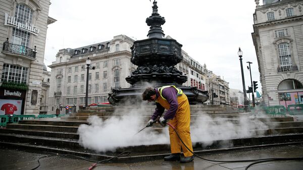 Рабочий чистит ступеньки, ведущие к Мемориальному фонтану Шафтсбери на площади Пикадилли в центре Лондона