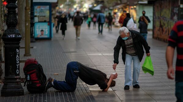 Мужчина подает милостыню нищему на бульваре в Барселоне