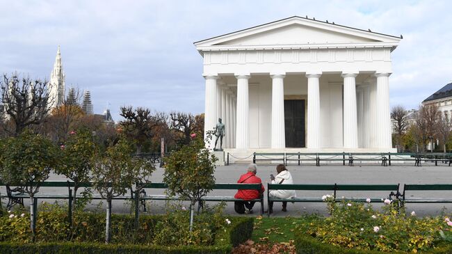 Люди сидят на скамейке в парке Фольксгартен в Вене