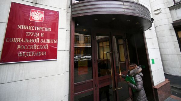 Женщина заходит в здание Министерства труда и социальной защиты Российской Федерации в Москве