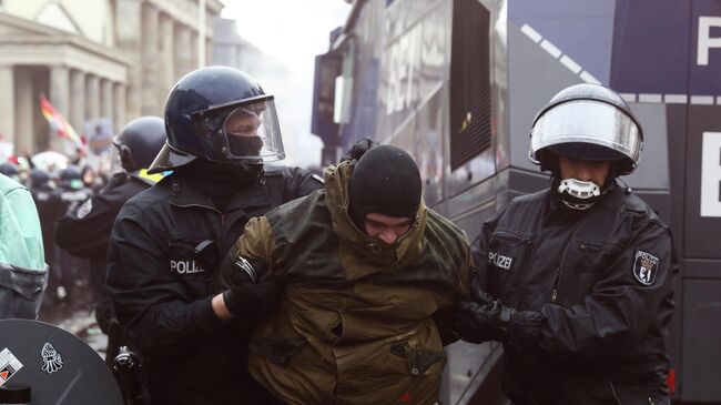 Полицейские задерживают участника протестов в Берлине