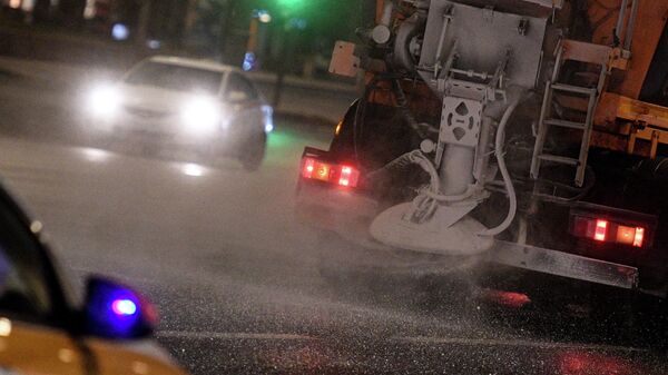 Снегоуборочная машина обрабатывает проезжую часть дороги противогололёдным средством в Москве