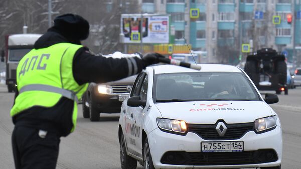 Сотрудник ДПС ГИБДД во время проверки соблюдения масочного режима водителями такси в Новосибирске