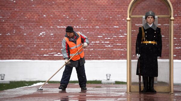 Мужчина убирает снег у Могилы Неизвестного Солдата у стен Московского Кремля