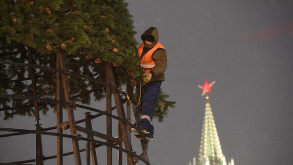 Рабочий устанавливает новогоднюю елку на Красной площади в Москве