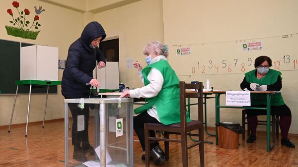 Женщина голосует во время второго тура парламентских выборов на избирательном участке в Тбилиси