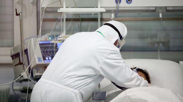 Медицинский работник около пациента в реанимационном отделении в ГБУЗ Волгоградская областная инфекционная больница No2 в Волгоградской области