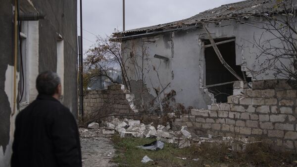 Мужчина возле частично разрушенного дома в Мартакерте