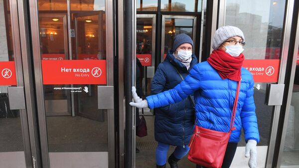 Девушки в защитных масках выходят у станции Московского метрополитена.