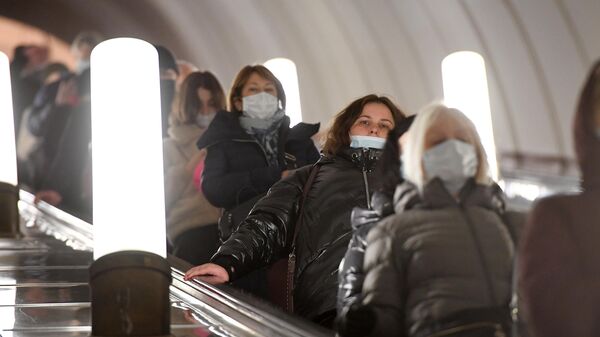Пассажиры в медицинских масках на эскалаторе Московского метрополитена