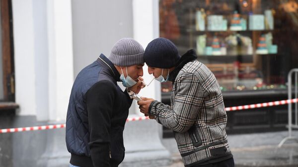 Мужчины в защитных масках на одной из улиц в Москве