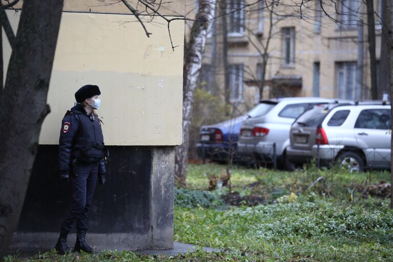 Сотрудница полиции у жилого дома в городе Колпино Ленинградской области, где мужчина держит в заложниках детей в квартире