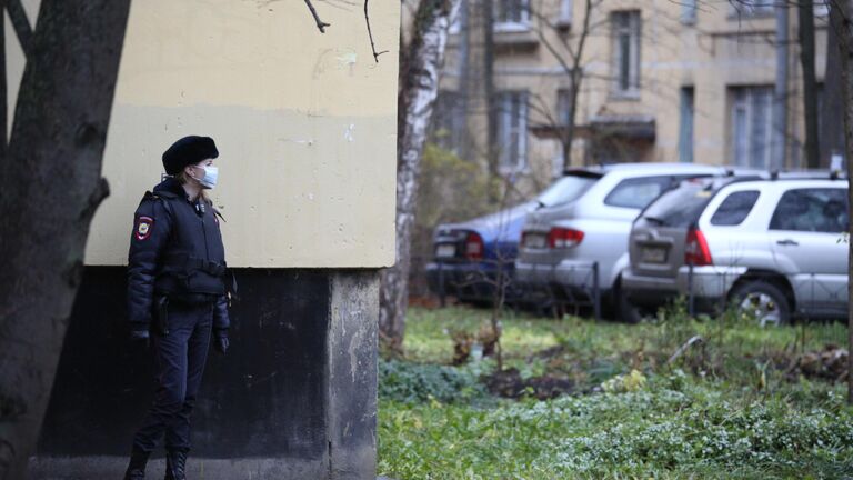 Сотрудница полиции у жилого дома в городе Колпино Ленинградской области, где мужчина держит в заложниках детей в квартире