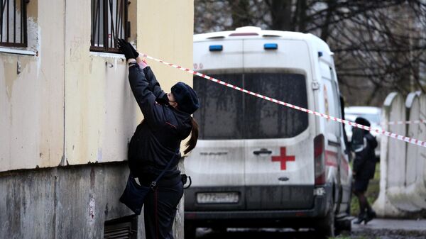 Сотрудница полиции натягивает оградительную ленту у жилого дома в городе Колпино Ленинградской области, где мужчина держит в заложниках детей в квартире
