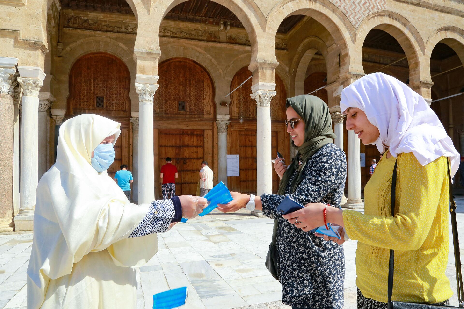 Женщина раздает защитные маски возле мечети аз-Зайтуна в Тунисе - РИА Новости, 1920, 25.11.2020