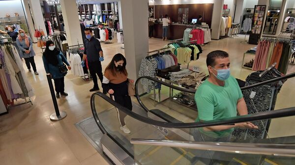 Покупатели в защитных масках соблюдают дистанцию в магазине одежды в Тунисе