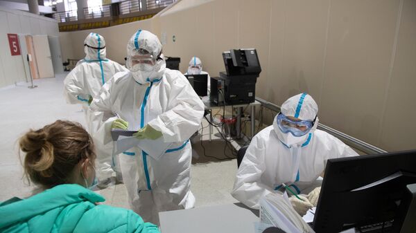 Медицинский работники приемного отделения осматривает пациентку во временном госпитале для пациентов с COVID-19, развернутом в ледовом дворце Крылатское