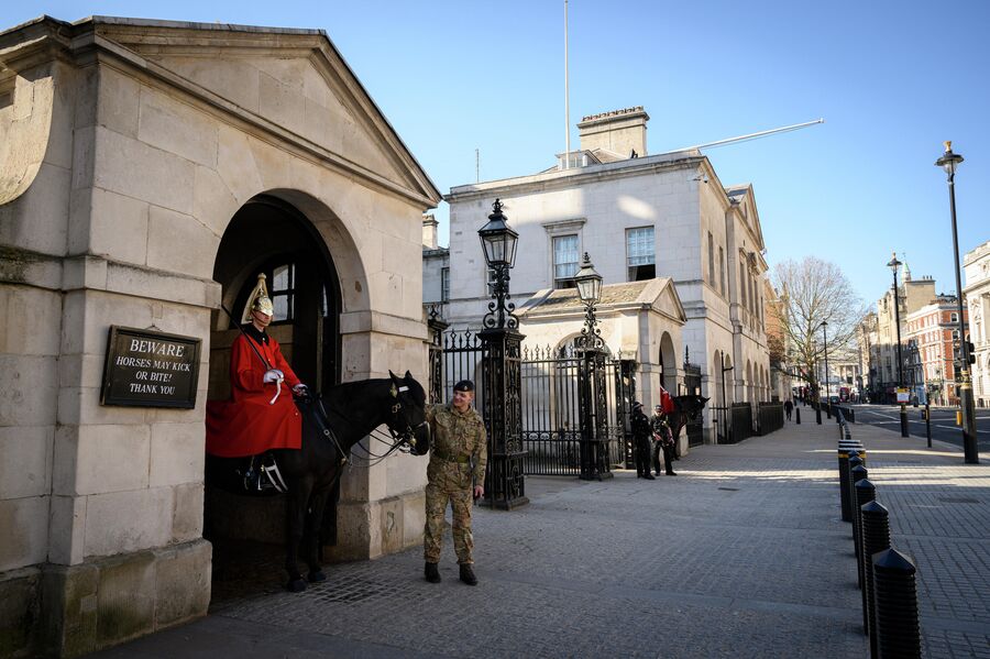 Конногвардеец королевского полка Британской гвардейской дивизии в карауле у здания своих казарм на лондонской улице Уайтхолл.