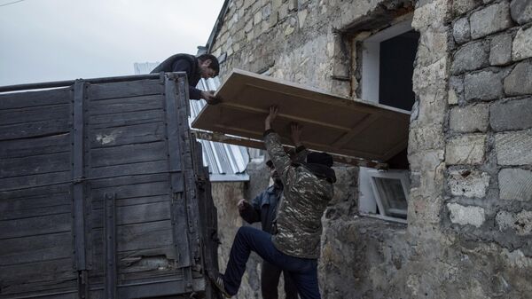 Мужчины загружают дверь в кузов грузового автомобиля в поселке Карегах в Нагорном Карабахе