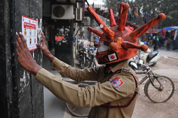 Волонтер гражданской обороны в шлеме на тему коронавируса Covid-19 в Нью-Дели