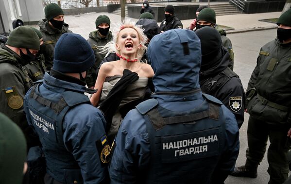 Сотрудники милиции задерживают активистку движения Femen протестующую у здания администрации президента Украины в Международный день борьбы за ликвидацию насилия в отношении женщин