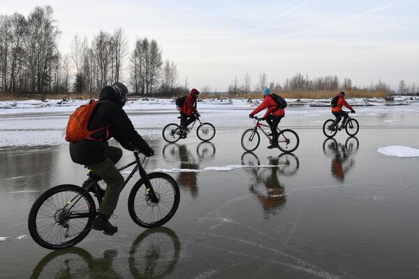 Велосипедисты катаются по льду водохранилища Новосибирской ГЭС возле острова Тань-Вань