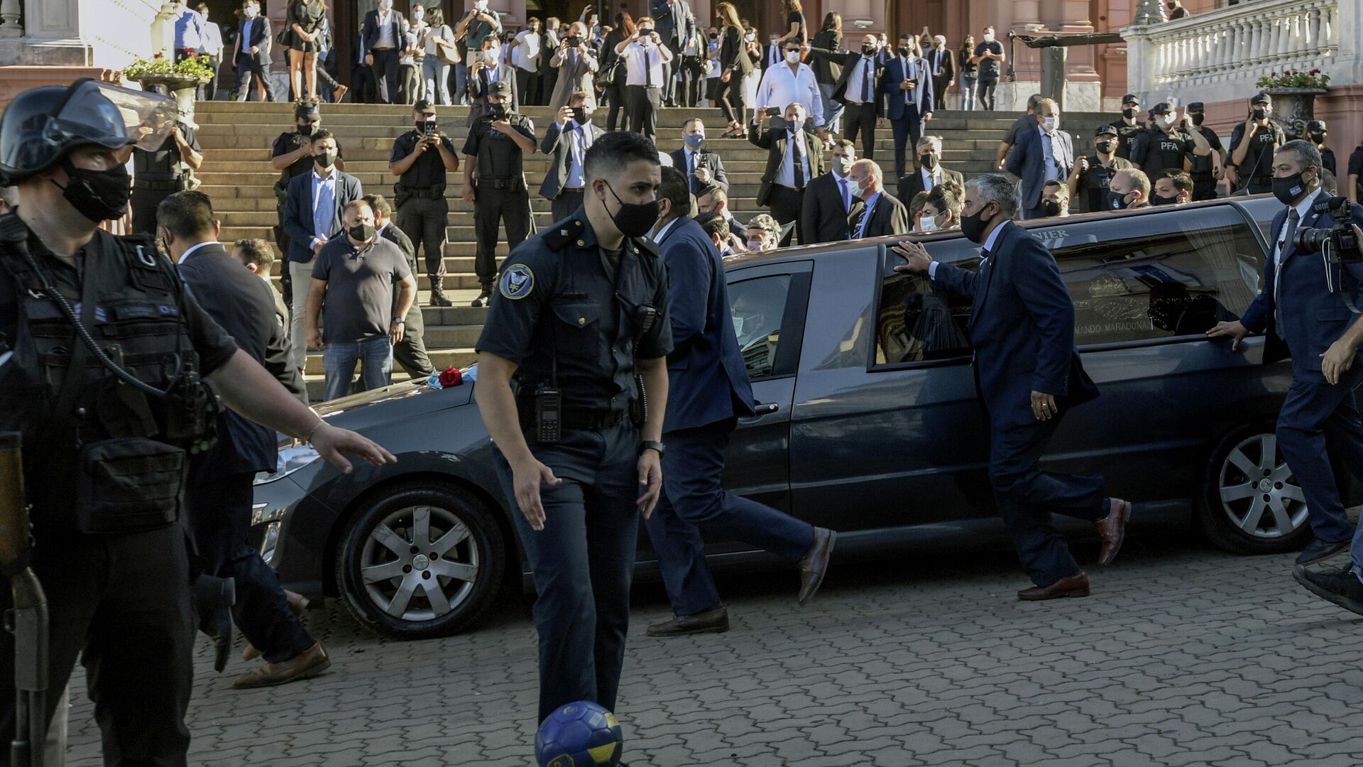 A policeman (C) controls a ball as the funeral cortege of late Argentinian football legend Diego Armando Maradona leaves the Casa Rosada government house to the cemetery, in Buenos Aires, on November 26, 2020. - Argentine football legend Diego Maradona -who died of a heart attack on the eve, at the age of 60- will be laid to rest in the Jardin de Paz cemetery on the outskirts of Buenos Aires, where his parents were also buried, Sebastian Sanchi told AFP. (Photo by JUAN MABROMATA / AFP) - РИА Новости, 1920, 27.11.2020