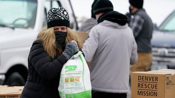 Волонтер с замороженной индейкой во время раздачи еды в рамках акции Банкет в коробке