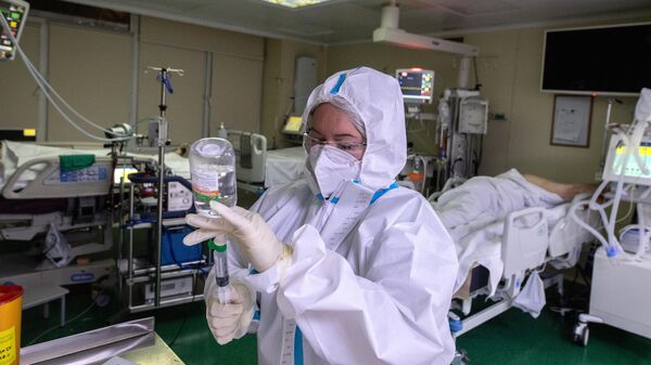 Медицинский работник и пациент в отделении реанимации и интенсивной терапии в госпитале COVID-19 в городской клинической больнице № 52 в Москве