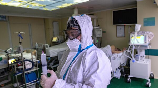 Медицинский работник и пациент в отделении реанимации и интенсивной терапии в госпитале COVID-19 в городской клинической больнице № 52 в Москве