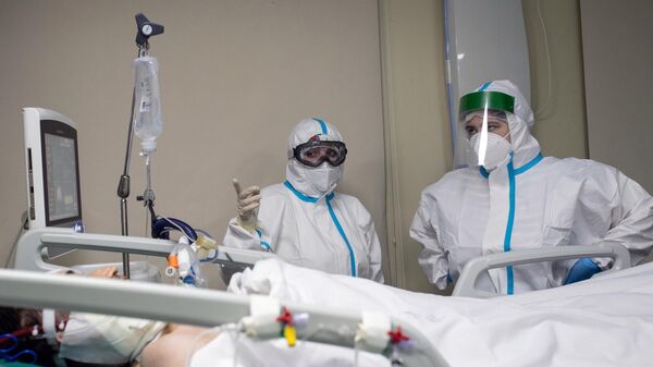 Медицинские работники и пациент в отделении реанимации и интенсивной терапии в госпитале COVID-19 в городской клинической больнице № 52 в Москве