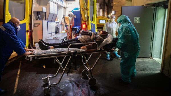 Медицинские работники доставляют пациента из машины скорой помощи в приемное отделение госпиталя COVID-19 в городской клинической больнице № 52 в Москве