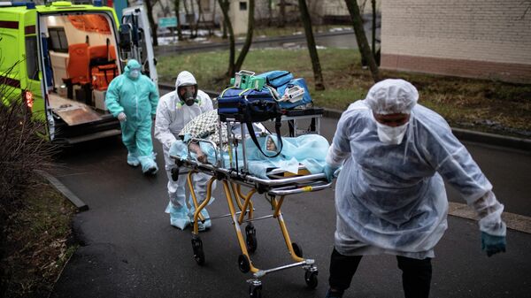 Медицинские работники доставляют пациента из машины скорой помощи в приемное отделение госпиталя COVID-19 в городской клинической больнице № 52 в Москве