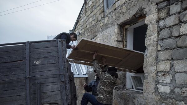 Мужчины загружают дверь в кузов грузового автомобиля в поселке Карегах в Нагорном Карабахе