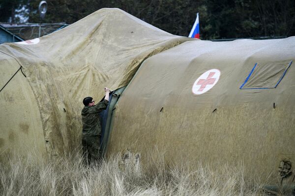 Российская военнослужащая закрепляет тент на каркасном модуле на территории мобильного полевого госпиталя неподалеку от Степанакерта