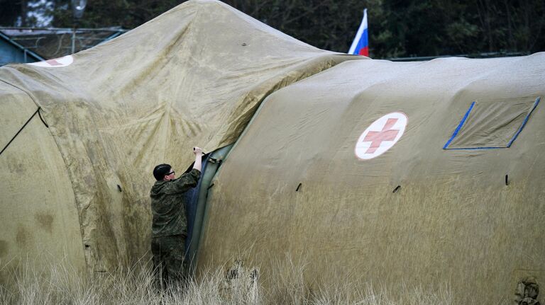 Российская военнослужащая закрепляет тент на каркасном модуле на территории мобильного полевого госпиталя неподалеку от Степанакерта