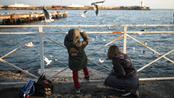 Женщина с ребенком гуляют по набережной Ялты