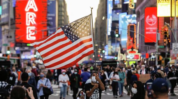 Мужчина с флагом США на Таймс-сквер в Нью-Йорке