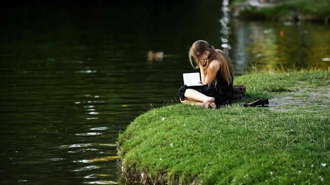 Девушка отдыхает у пруда в парке