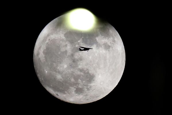 Частный самолет пролетает мимо бобровой луны около аэропорта имени Бен-Гуриона в Тель-Авиве, Израиль 