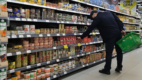 Покупатель выбирает консервы в супермаркете 